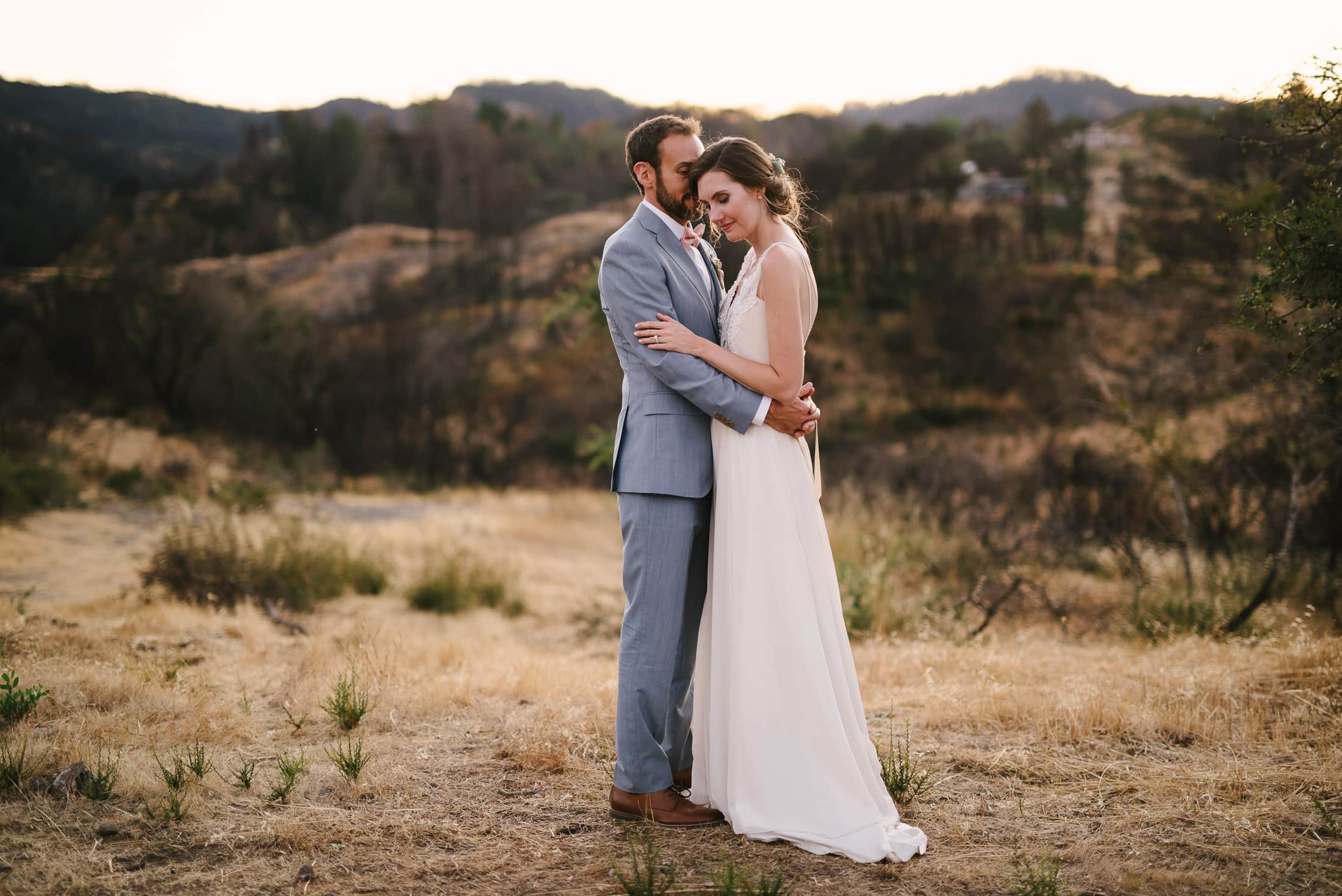 Couple embracing in front of rolling hills at the Triple S Ranch in Calistoga