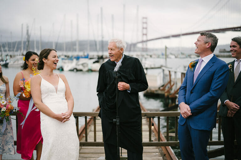 Couple laughing at Travis Marina wedding with boats and Golden Gate Bridge in background