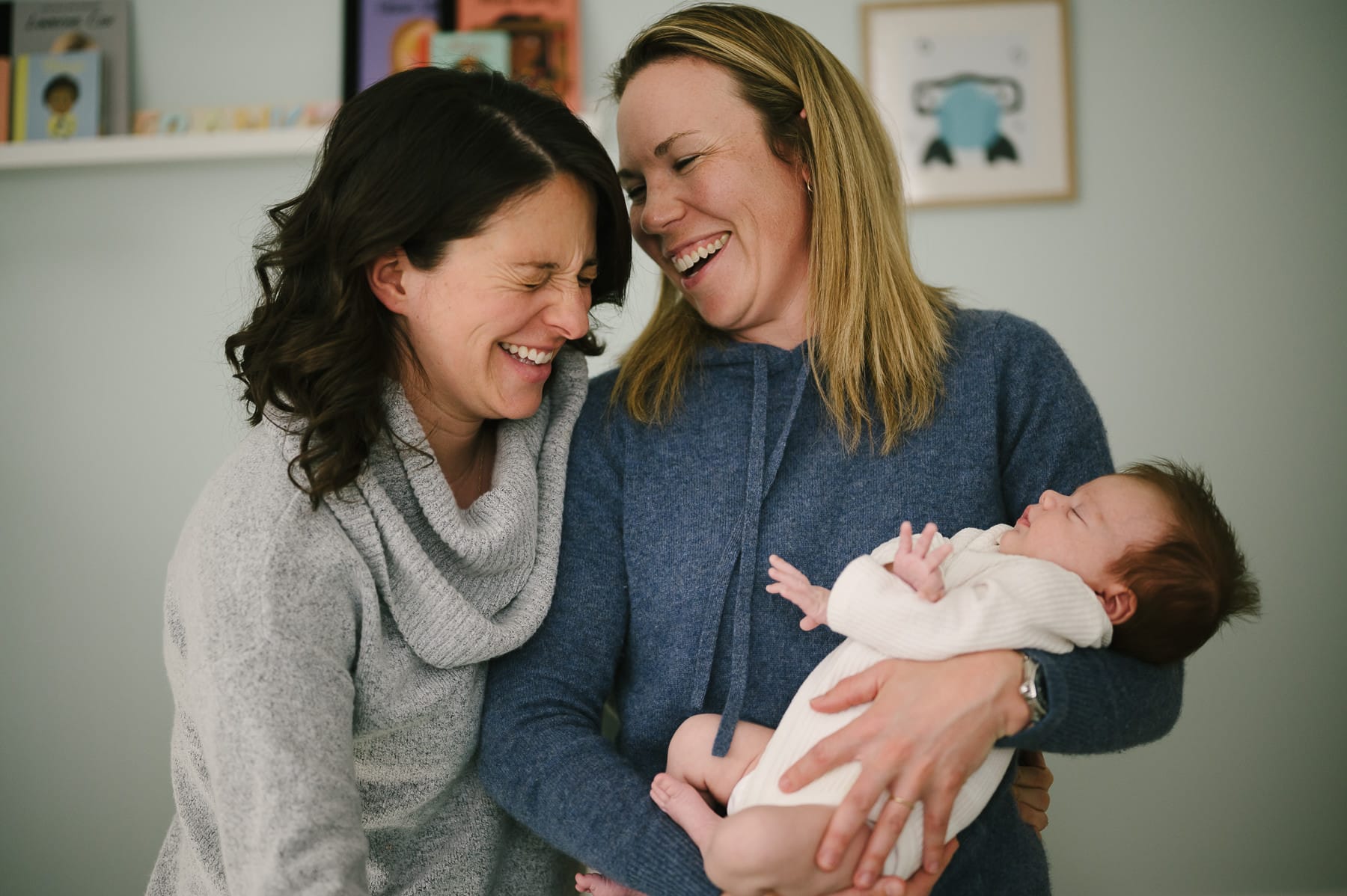 Same sex couple holding new born baby and laughing at family portrait session in Orinda