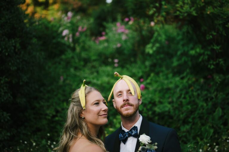 Bride and groom with banana peels on their head in front of lush green background at Sand Rock Farm in Aptos