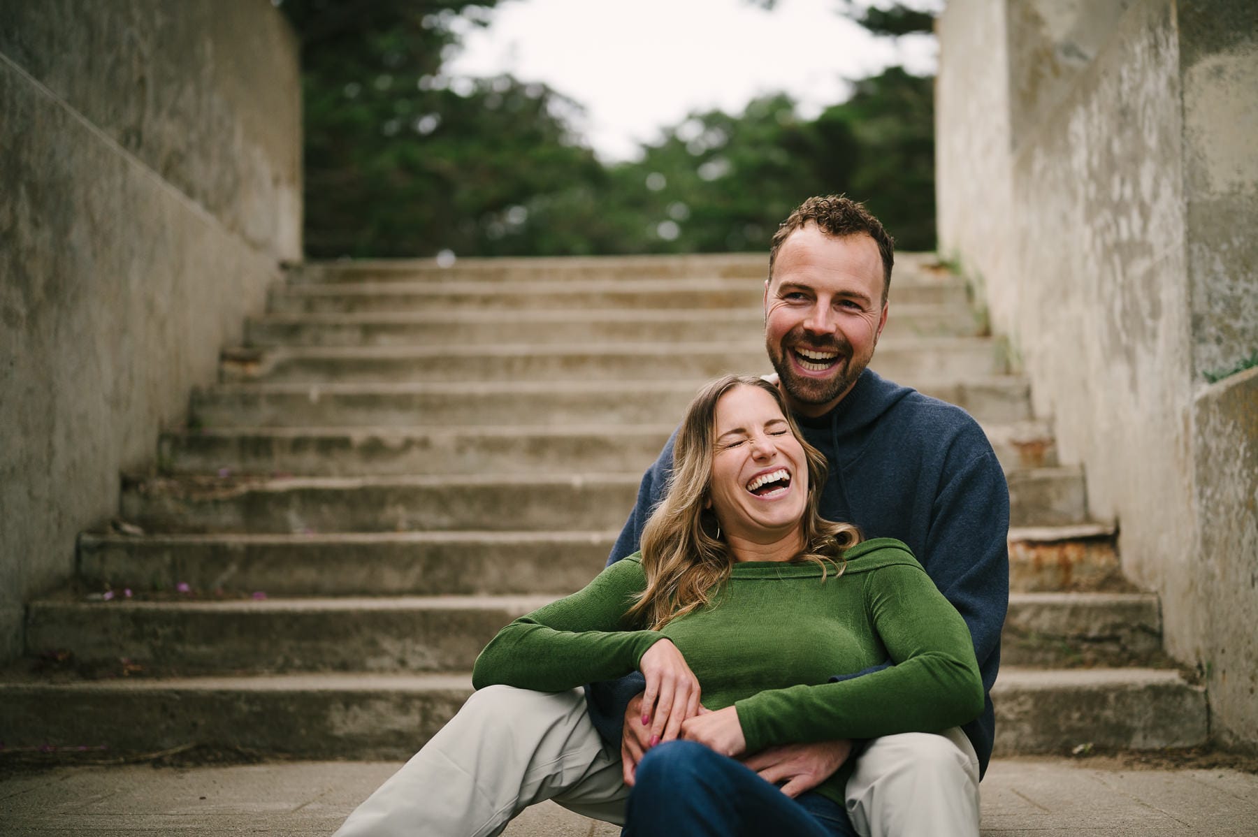 Couple sitting on steps and laughing at engagement session in Sutro Park in San Francisco.
