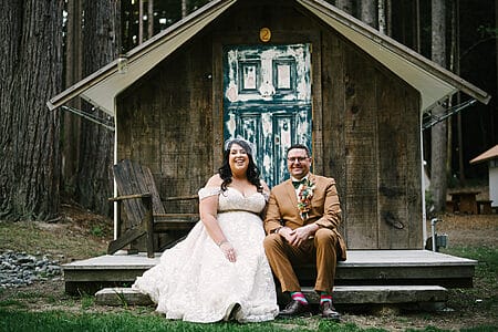 Wedding couple sitting on porch in front of rustic tent cabin at Heartwood wedding in Mendocino