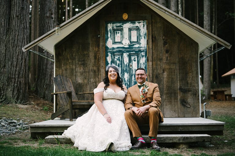 Wedding couple sitting on porch in front of rustic tent cabin at Heartwood wedding in Mendocino